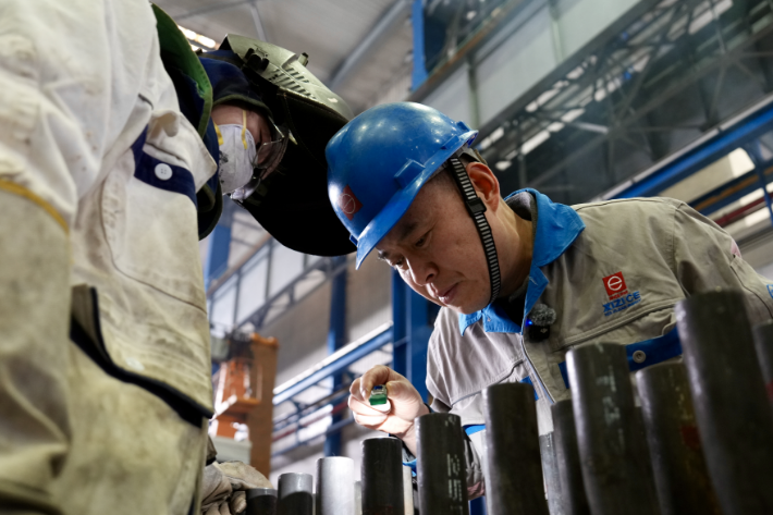 葛小青(右)检查徒弟的焊接成果,指导教学 周旭辉/摄